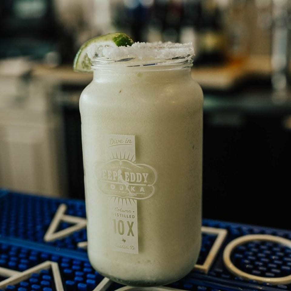 A Deep Eddy Vodka mason jar filled with a frozen drink, garnished with a lime wedge and salt.