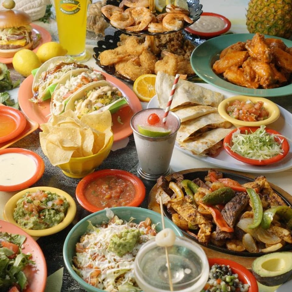 A vibrant spread of Mexican dishes including tacos, fajitas, quesadillas, chips, and drinks.