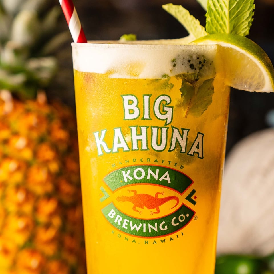 Golden cocktail garnished with mint and lime in a Big Kahuna glass.