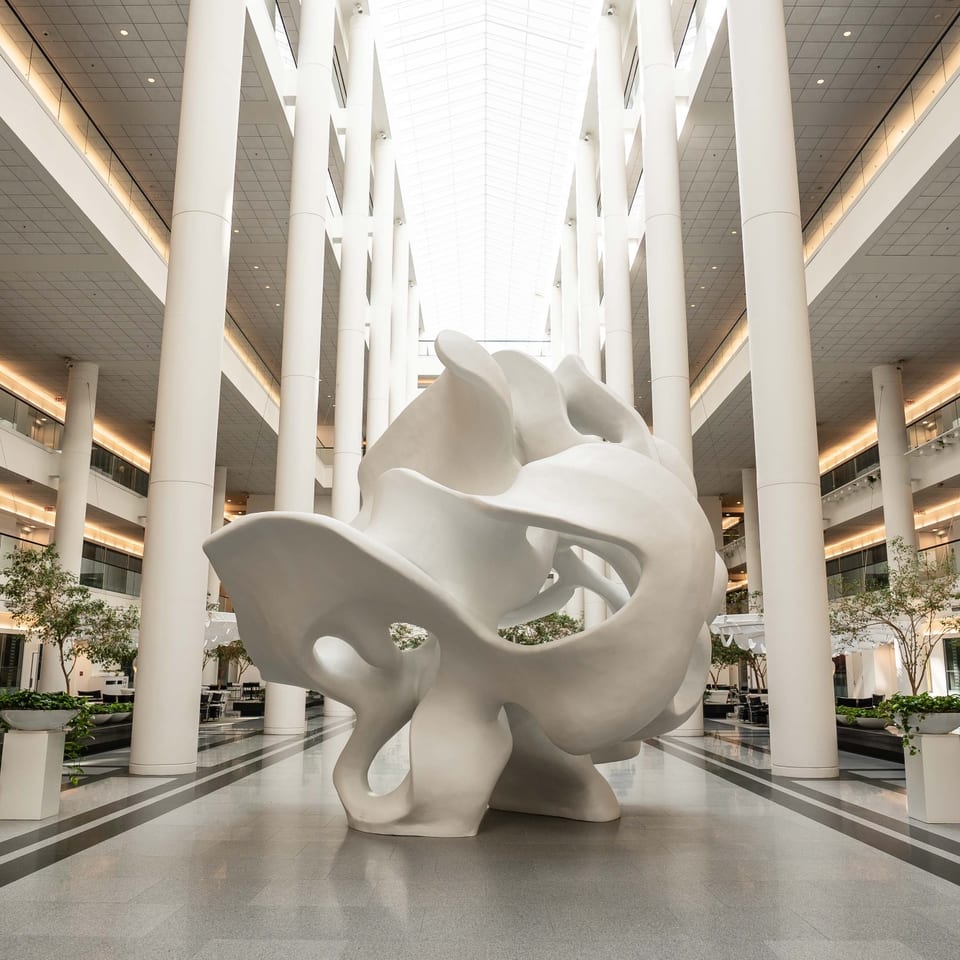 White abstract sculpture surrounded by tall columns in the Garden Atrium.